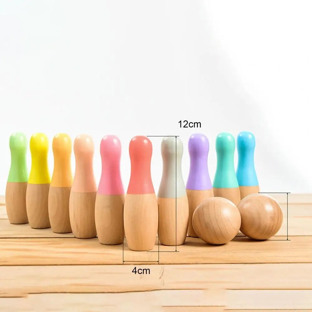 A collection of colorful wooden InvenToy Montessori Bowling Set pins and balls on a wooden surface, with dimensions labeled, against a plain white background.
