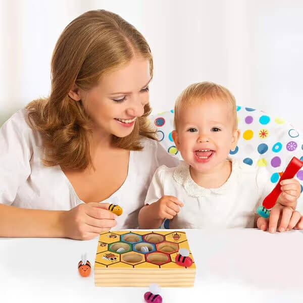 A joyful woman and a toddler playing with colorful InvenToy Montessori Bee Boxes on a white background. The child is holding a red piece while the woman smiles encouragingly.