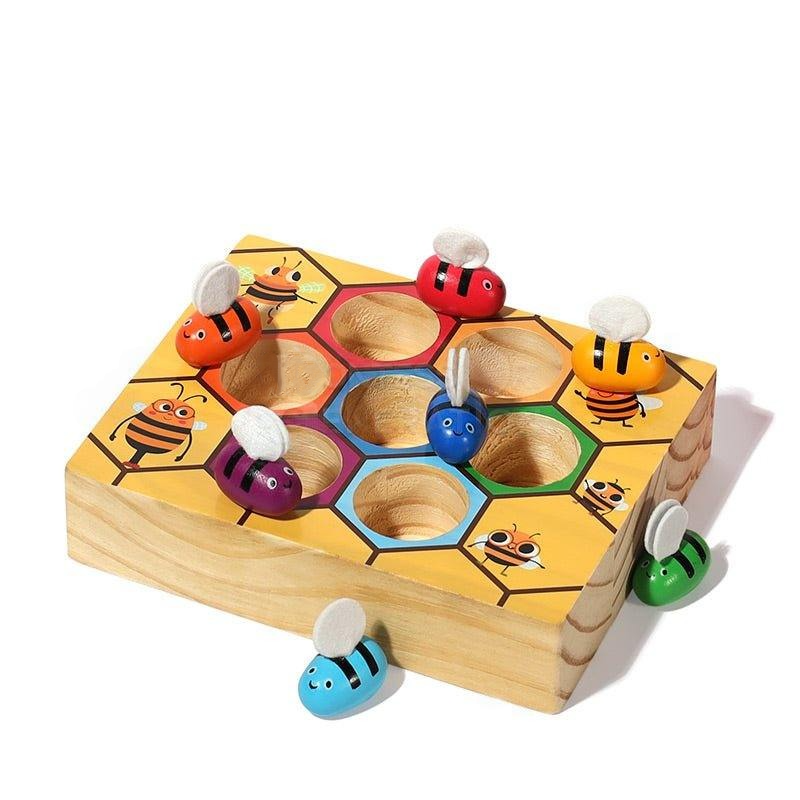 Colorful wooden InvenToy Montessori Bee Box featuring a honeycomb design with various cartoon-style bees inserted in cylindrical holes, set against a white background.
