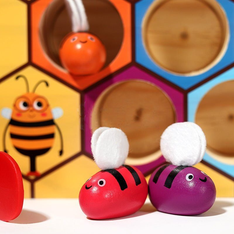 Colorful InvenToy Montessori Bee Boxes featuring bee and ladybug designs displayed in front of a hexagonal shelf backdrop with vibrant colors.