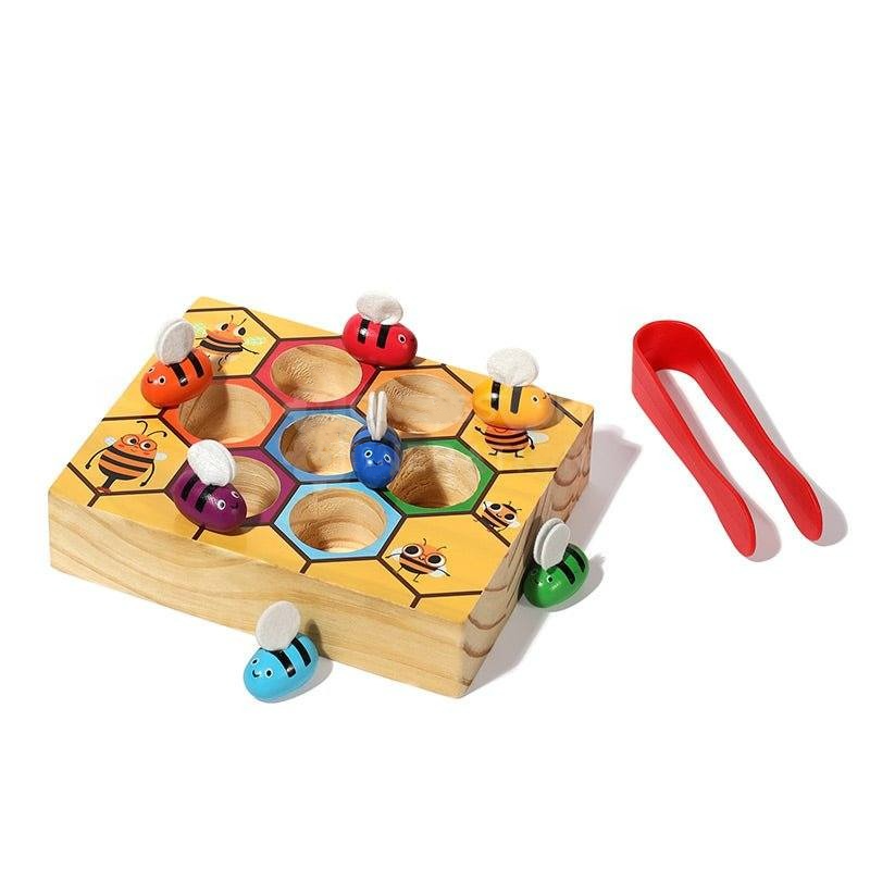 A InvenToy Montessori Bee Box with colorful bees in pockets and a pair of red tongs, designed to develop fine motor skills. The bees have cartoon faces and are set against a white background.