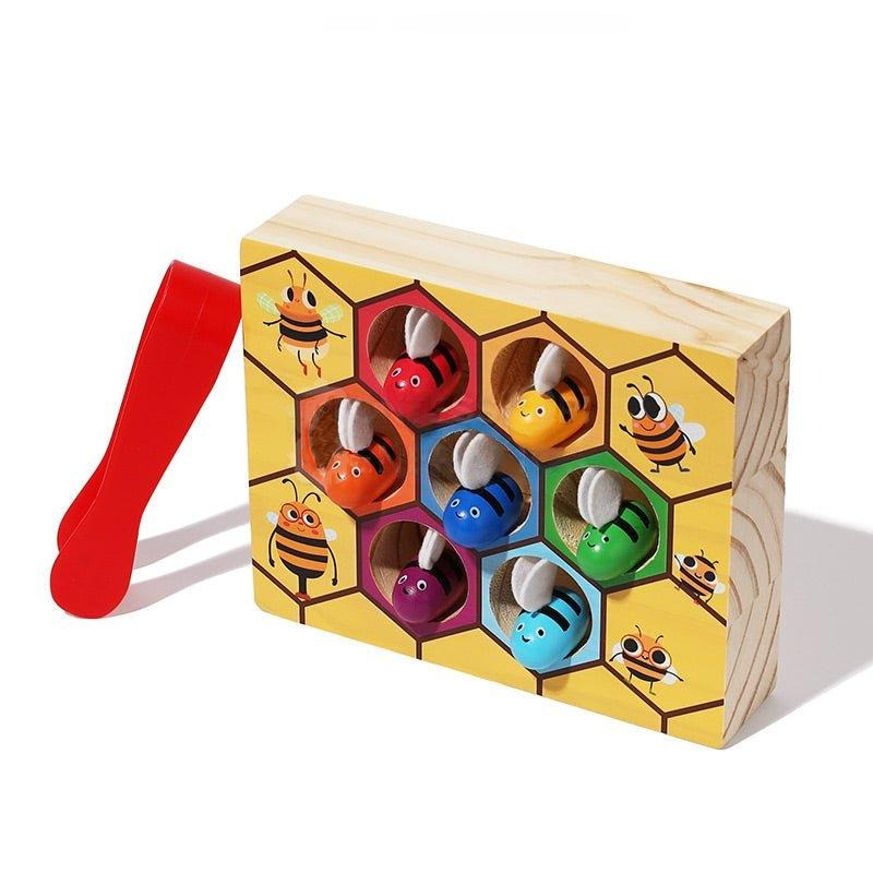 A wooden InvenToy Montessori Bee Box featuring colorful cartoon bees and insects in hexagonal holes, each with a red plastic mallet on the side, on a white background.