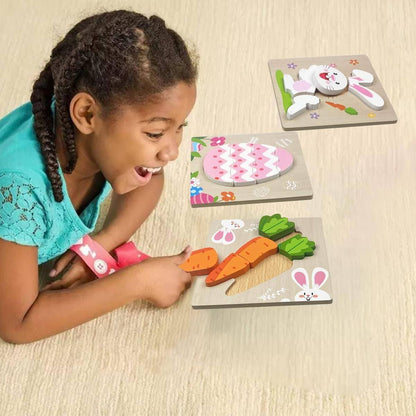 A young girl with braided hair smiles while playing with colorful InvenToy Montessori Easter Wooden Puzzles (4 Pack) on the floor, featuring rabbit and carrot designs.
