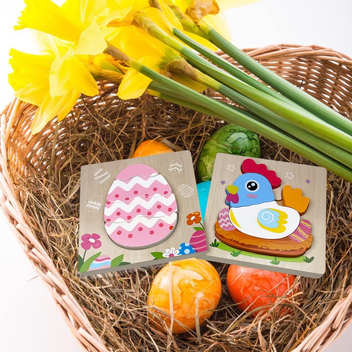 A festive Easter arrangement featuring a wicker basket with painted eggs, colorful InvenToy Montessori Easter Wooden Puzzles (4 Pack) with an egg and a duck design, and a bouquet of yellow daffodils on a white background.