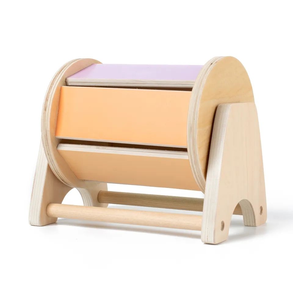 A Montessori Spinning Drum with orange and purple napkins, featuring a curved design and a base with two wooden rods. It is set against a white background and resembles an InvenToy creation.