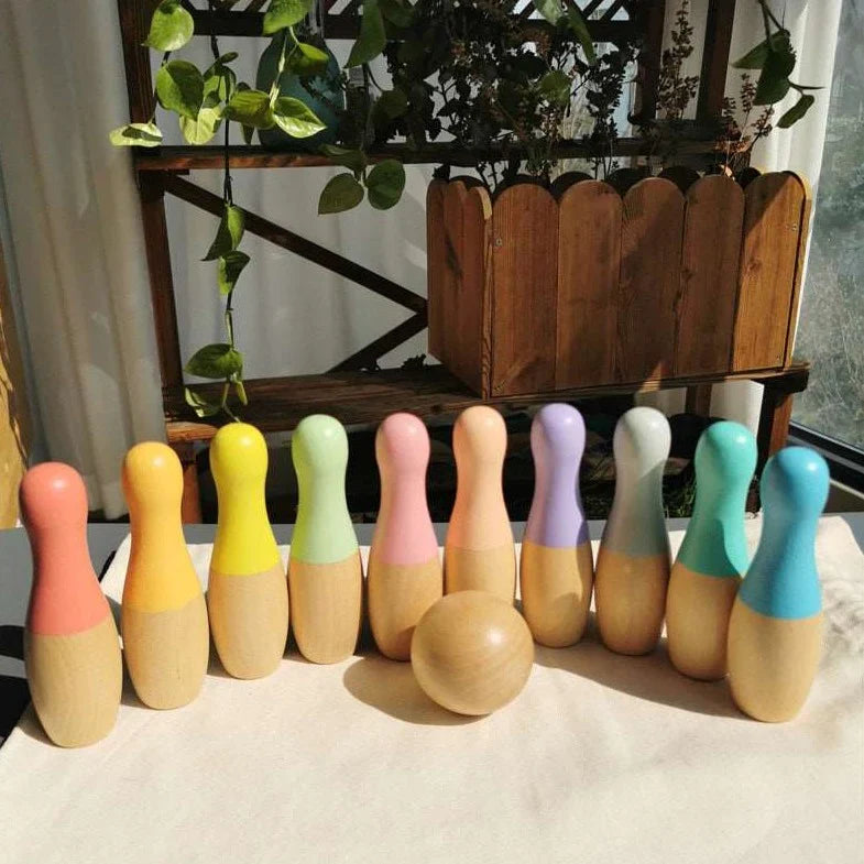 A set of colorful InvenToy Montessori Bowling Set on a windowsill, bathed in sunlight, with indoor plants and a wooden shelf in the background, perfect as Montessori baby toys.