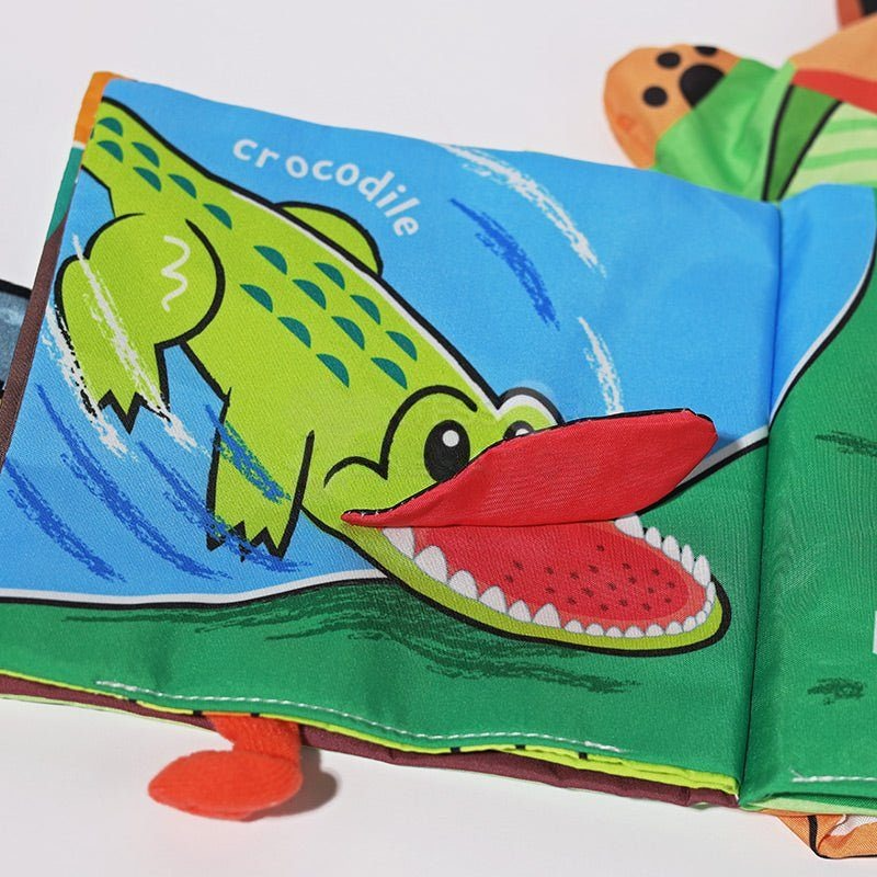Colorful InvenToy Montessori Baby Cloth Book open on a page featuring a bright green and red crocodile illustration, with the word "crocodile" written above it.