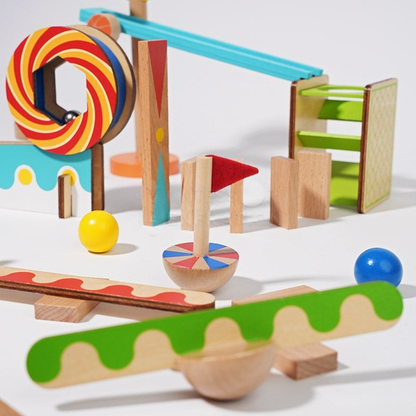 An assortment of colorful InvenToy Montessori Domino Run including building blocks, a spinning top, balls, and intricately designed pieces on a white surface, arranged to suggest motion and play.