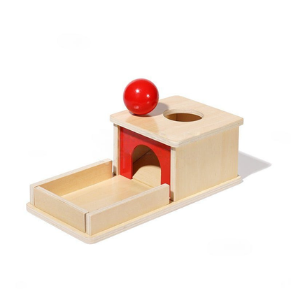 A InvenToy montessori object permanence box with a red ball on top, designed to teach infants that objects still exist even when they cannot be seen. This inventoy fosters early cognitive development in a