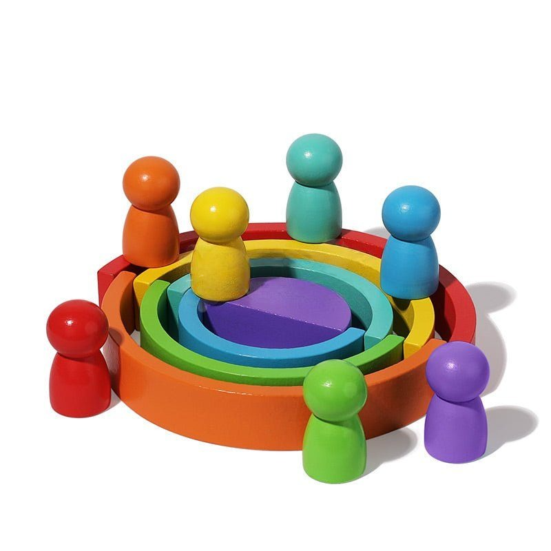 Colorful wooden InvenToy Montessori Rainbow nesting bowls surrounded by matching balls on a white background, arranged in a rainbow sequence of red, orange, yellow, green, blue, and purple.