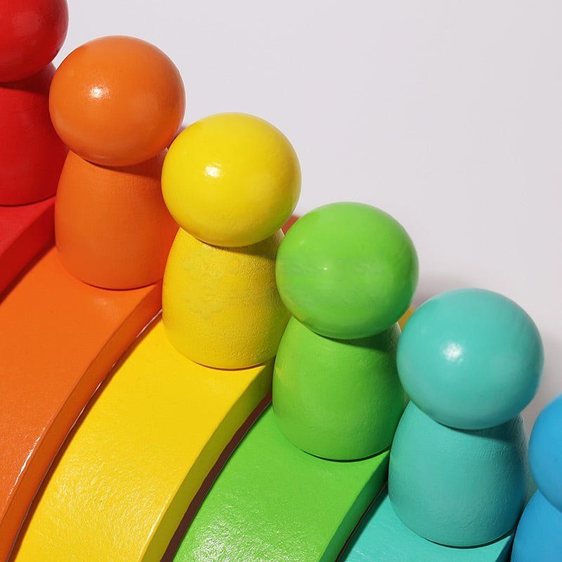 Colorful InvenToy Montessori Rainbow toy with rainbow arches and balls painted in bright red, orange, yellow, green, and blue, set against a white background.