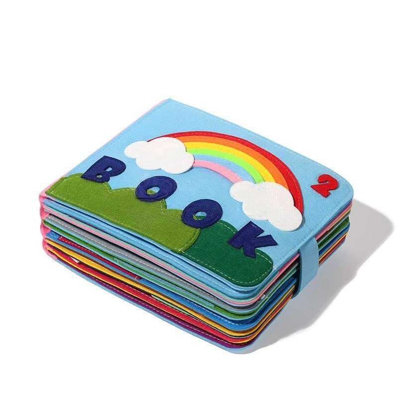 A colorful InvenToy Montessori Story Book with a cover depicting a rainbow, clouds, and the word "book". The book is layered with multiple colored pages visible from the side.