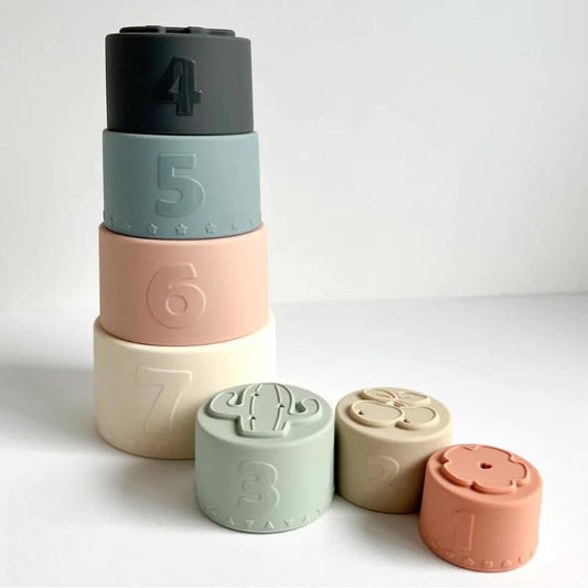 A stack of five round, colorful InvenToy Montessori Baby Stacking Cups with numbers on the tops, arranged in ascending order from top to bottom against a plain white background.