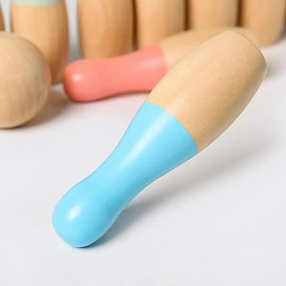 Close-up of a blue and natural wood mini InvenToy Montessori Bowling Set, with blurred pins in pink and natural wood colors in the background.