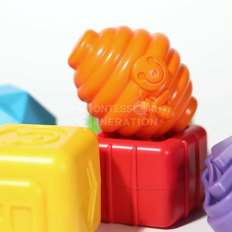 A close-up of colorful Montessori Shape Blocks by InvenToy, shaped like a twisted orange coil on red blocks, with parts of blue and yellow blocks visible in the background.